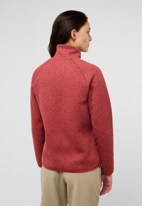 Roter, strukturierten Zip-Kragenpullover mit hohem Kragen und langen Ärmeln; verfügt über Raglan-Nähte und ein leichtes Saumdetail am unteren Ende.