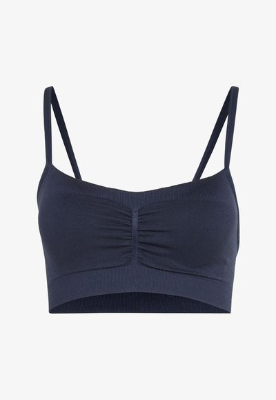 Dark blue seamless bralette with thin adjustable straps and ruched center front detail on a white background.