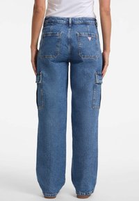 Weite Jeans-Cargo-Hosen in Mittelblau. Merkmale sind große Seitentaschen, verstärkte Nähte und ein klassisches Fünf-Taschen-Design.