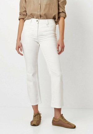White cropped jeans with a button closure and front pockets, paired with brown lace-up sneakers featuring mesh detailing.