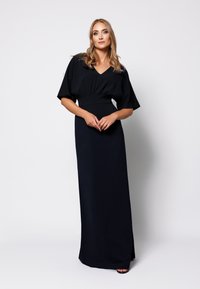 Długa czarna sukienka z krótkimi, szerokimi rękawami i dekoltem w kształcie litery V. Dopasowany stan, gładka faktura i długość do podłogi. Prosta i elegancka.