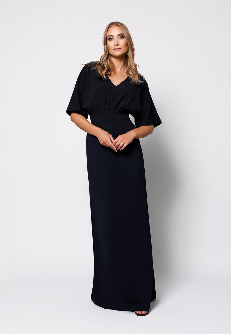 Długa czarna sukienka z krótkimi, szerokimi rękawami i dekoltem w kształcie litery V. Dopasowany stan, gładka faktura i długość do podłogi. Prosta i elegancka.