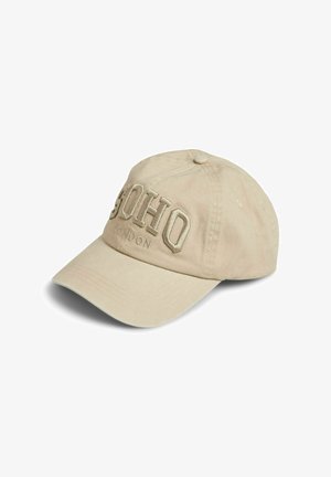 Casquette de baseball en coton beige avec une visière courbée, présentant une broderie en relief avec l'inscription "SOHO" et un texte plus petit "LONDON" à l'avant.