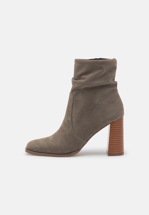 Szary zamszowy botek na kostkę o luźnym fasonie, z zakończeniem w szpic i 10 cm drewnianym słupkowym obcasem z poziomymi paskami.