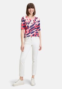 Short-sleeve top with a pink, navy, and white leopard print design. Made of soft fabric, paired with white pants and white sneakers.