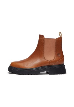 Botte Chelsea en cuir marron avec panneaux latéraux élastiques, semelle noire épaisse, languette et logo embossé sur le talon.