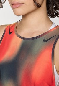 Czarna koszulka sportowa Nike z abstrakcyjnym gradientem czerwieni, pomarańczu i czerni, z czarnym logo oraz kontrastowym detalem ściegów.
