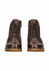 Brązowe skórzane botki sięgające za kostkę mają okrągły czubek, sznurowane z przodu, z zamkami błyskawicznymi z boku oraz fakturowaną brązową podeszwę dla lepszej przyczepności.