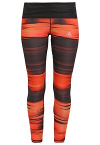 Leggings présentant un design dégradé avec des rayures orange vif et noires. Fabriqués en tissu extensible avec une taille noire et le logo Adidas.