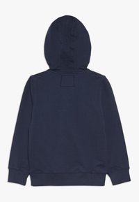 Sudadera azul marino, material de mezcla de algodón, cuenta con capucha, puños acanalados y un parche rectangular encima del cuello. Textura suave.