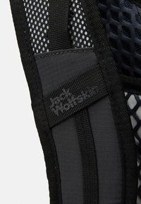 Sangle en tissu et en maille noire avec une étiquette de logo texturée. Le design comprend des matériaux légers et un motif en treillis pour la ventilation.