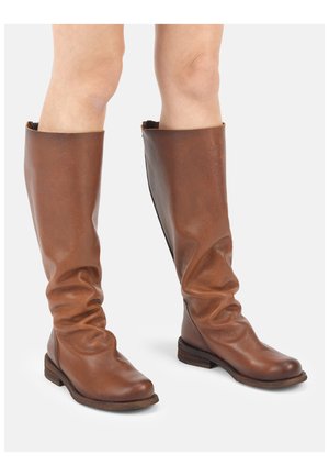Brązowe kozaki sięgające do kolan, wykonane ze skóry, o luźnym fasonie, zaokrąglonych noskach i niskich, drewnianych obcasach, noszone na gołe nogi.
