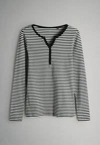 Mustriga musta ja valge pikavarrukaline särk, millel on V-kujuline kaelus, nööpide aktsendid, sooniktekstuur ja sirge äär. 