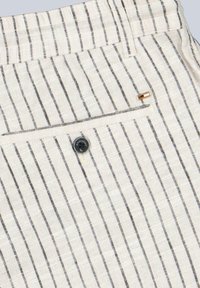 Striped linen fabric in cream with thin black lines. Features a back pocket with a button closure and a small metal logo accent.