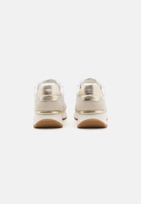 Metallisch goldene und weiße Sneakers mit strukturierten Oberflächen, runder Form, gepolstertem Kragen und kontrastierenden Gummisohlen.