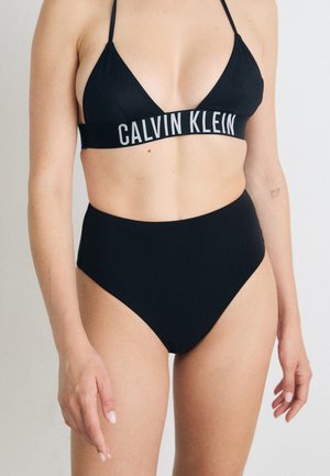Crni bikini set s trokutastim topom s CALVIN KLEIN logom i visokim gaćicama, glatke teksture i minimalističkog dizajna.