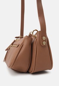 Brown leather handbag with a textured finish, featuring gold hardware, a zipper pocket, and two compartments with a short strap.