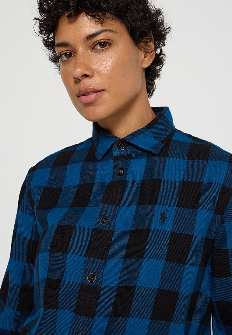 Camicia a maniche lunghe a scacchi blu e nera con colletto, realizzata in tessuto testurizzato, con bottoni neri e un piccolo logo sul petto.