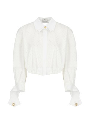 White cropped blouse with a classic collar, embellished with small dots, and billowy sleeves featuring gold accents at the cuffs.