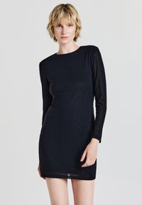 Schwarzes, langärmliges Minikleid mit figurbetonter Form, das eine strukturierte Oberfläche aufweist, die mit kleinen Nieten verziert ist.
