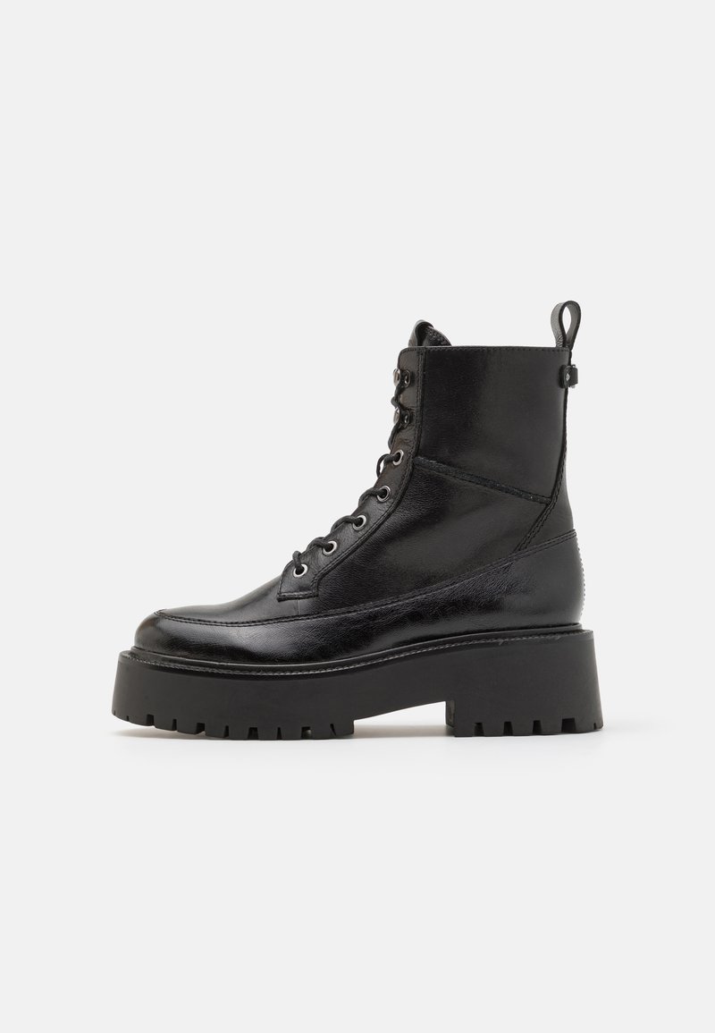 Botas de cuero negro hasta el tobillo con punta redonda, parte delantera con cordones, ojales reforzados y suela de plataforma gruesa. Presilla trasera para ponerlas con facilidad.
