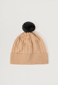 Knit beanie in a light beige color, featuring a textured cable design, ribbed cuff, and a black pom-pom at the top.