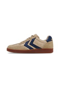 Beige suede sneaker with navy accents, featuring a patterned upper, flat laces, rounded toe, and a brown rubber sole.