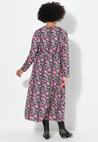 Blumenkleid mit langen Ärmeln, verziert mit rosa und weißen Blumen auf schwarzem Hintergrund, mit tailliertem Schnitt und knöchellanger Länge.