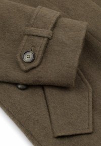 Brązowa wełniana tkanina na płaszcz o miękkiej fakturze, z zapięciem na guziki i naszywaną kieszenią na rękawie.