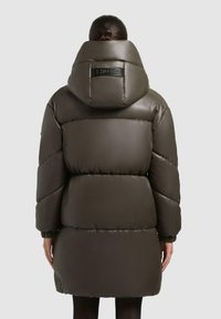 Puchowa parka do kolan w ciemnooliwkowym kolorze, z dużym kapturem, elastycznymi mankietami i logo na plecach. Gładka tekstura.