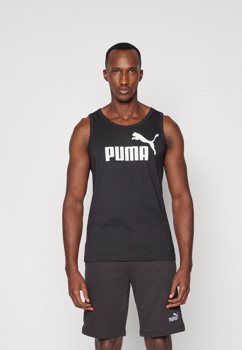 Svart tanktopp med hvit "PUMA" logo på brystet. Stoffet ser glatt og lett ut. Kombinert med mørke shorts med liten logo.