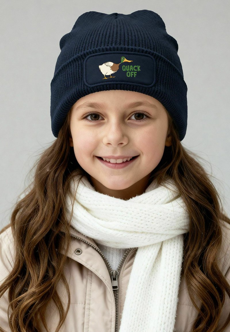Knitted navy beanie with a ribbed texture and a rectangular patch featuring a duck and the text "QUACK OFF." Worn with a white scarf.