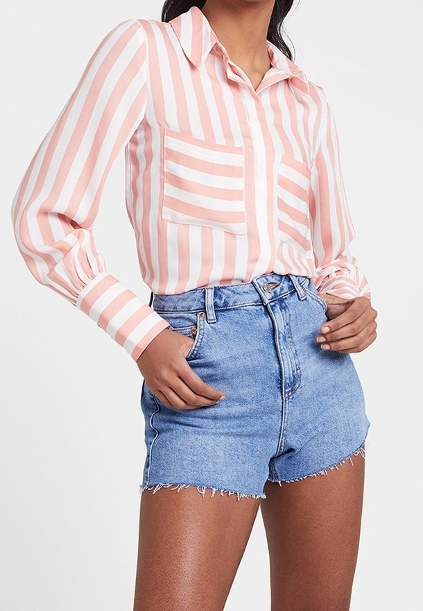 Camicia a maniche lunghe a righe rosa e bianche con colletto e tasca; abbinata a pantaloni di denim a vita alta con orli sfrangiati.