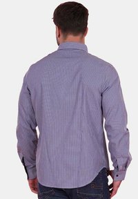 Chemise à manches longues à carreaux en violet et blanc. Dotée d'un col classique, de poignets à boutons et d'un ourlet arrondi. Fabriquée en tissu lisse.