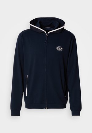 Sötétkék cipzáras kapucnis pulóver puha anyagból, ellentétes fehér szegéllyel a kapucnin, az elülső zsebeknél és hímzett logóval díszítve.