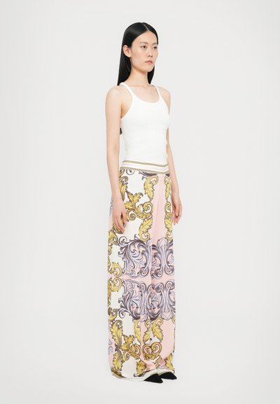 Fustă maxi cu modele florale elaborate în nuanțe de aur și lavandă pe un fundal pastelat moale, combinată cu un tricou alb ajustat.