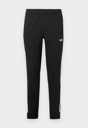 Pantaloni sportivi neri realizzati in un tessuto liscio. Presentano una vita elastica, tasche laterali e strisce bianche lungo le gambe.