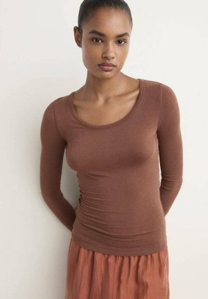 Blusa marrón de manga larga con un escote redondeado, hecha de un material suave y ajustado. El diseño presenta un ligero fruncido a lo largo de los lados.