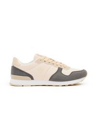 Zapatilla beige y gris con materiales de malla y ante, puntera redonda, cordones y una entresuela blanca. Presenta un logo redondo en el lateral.