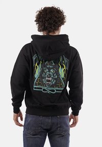Felpa nera con cappuccio e una grafica che presenta la testa di un lupo, accenti blu e gialli e motivi di fulmine. Tessuto morbido, cappuccio con coulisse.