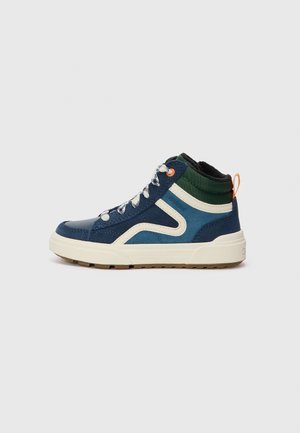 Niebiesko-zielony wysoki sneaker z białą podeszwą, białymi sznurówkami, pomarańczową pętelką do ściągania i beżowymi elementami z zamszu na jednolitym tle.