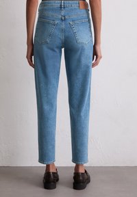 Jasnoniebieskie dżinsy z wysokim stanem, prostą nogawką i delikatnym przetarciem. Posiadają dwie tylne kieszenie oraz skórzaną naszywkę w pasie.