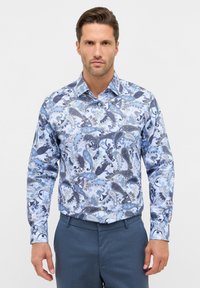 Langarmshirt met een blauw paisleypatroon op een lichtblauwe achtergrond. Gemaakt van stof met een gladde textuur; met een button-down kraag.