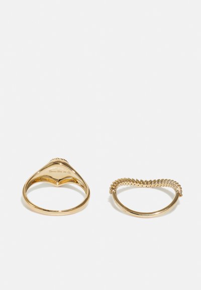 Two gold rings: one with a curved, textured band and a decorative top, the other with a spiral design. Both have a shiny finish.