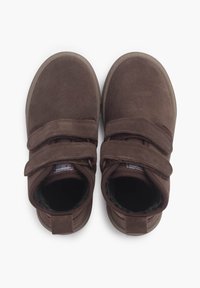 Hnědé semišové boty na suchý zip, kulatá špička a měkká vnitřní podšívka. Ploché gumové podrážky a přizpůsobený design kotníku.