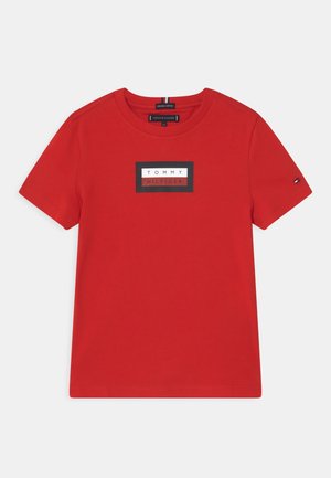 Rød kortærmet bomulds-T-shirt med et sort-hvidt rektangulært Tommy Hilfiger-logo centreret på brystet.