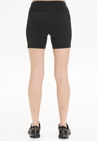 Zwarte sportshorts met een hoge tailleband, een gladde textuur en twee zijzakken, weergegeven vanaf de achterkant. Geschikt voor actieve kleding.