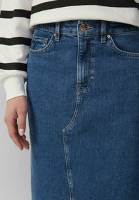 Denim rok in donkerblauw, met een hoge taille, voorzakken en minimale stiksels. De textuur lijkt soepel en stevig.