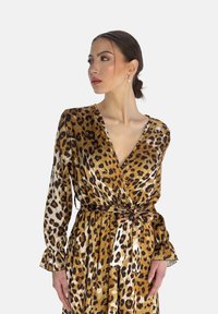 Leopardmönstrad omslagskl�änning i brunt och guldtyg, med långa ärmar, V-ringning och ett tygbälte för justering.