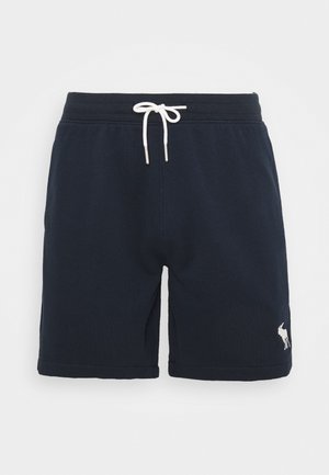 Pantaloncini in cotone blu navy con vita con coulisse e terminali in argento, e un piccolo logo bianco sulla parte inferiore della gamba sinistra. Texture morbida e vestibilità casual.